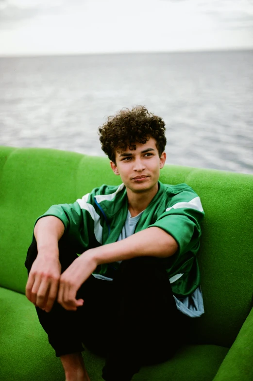 a young man sitting on top of a green couch