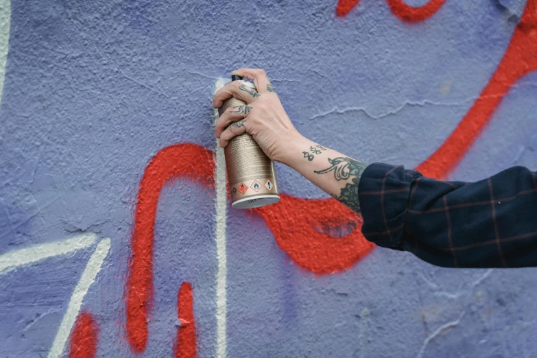 an individual painting on a wall with a spray paint roller