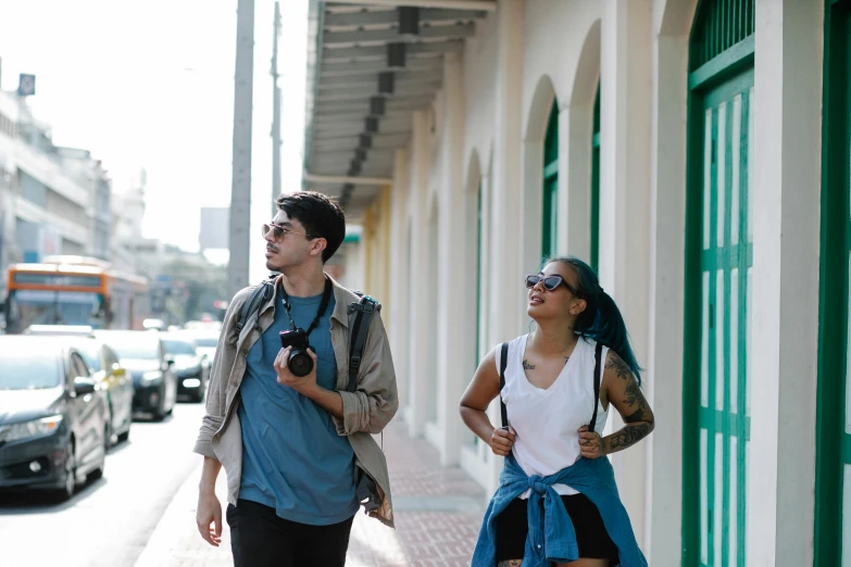man and woman walking on the sidewalk with an old style po camera