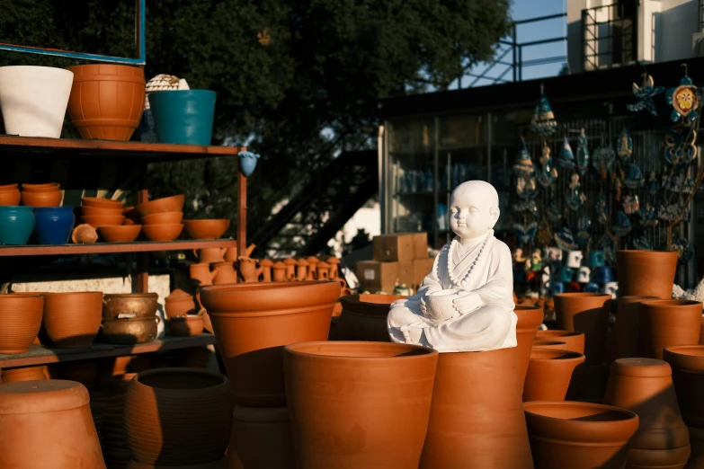 a statue in front of several clay pots