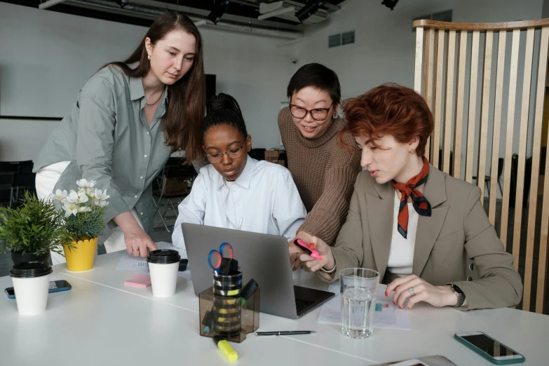 a group of people are gathered around a laptop computer