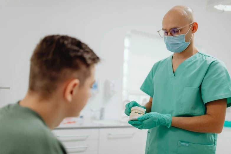 a man with a surgical mask and a syosh is talking to a nurse