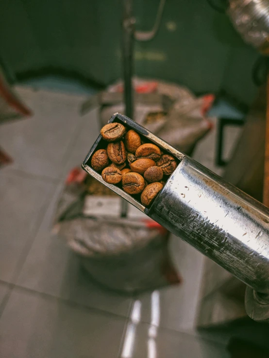 a hand is holding a metal object with almonds inside