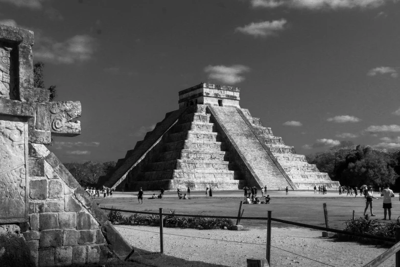 people walk around a large pyramid near other ruins