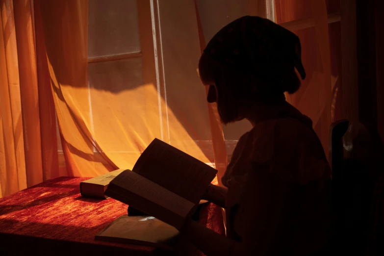 silhouette of child reading in light of window