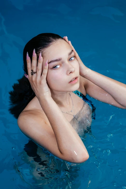 a woman holds her hands behind her head in the blue pool