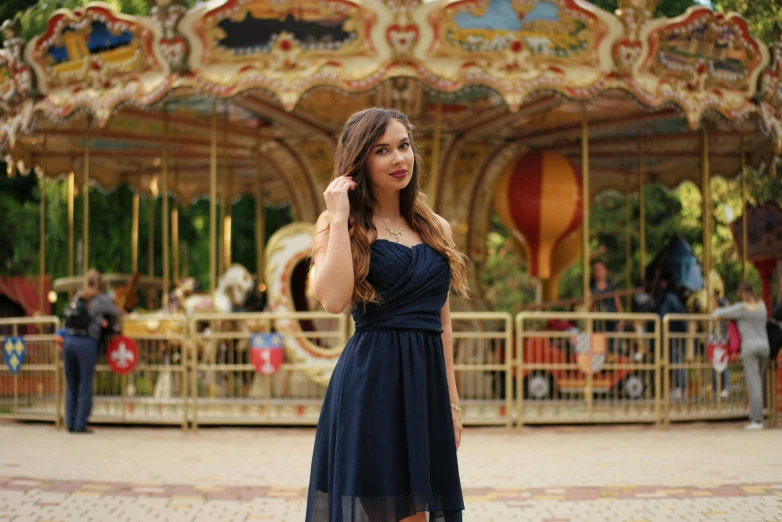 a woman stands in front of a colorful carousel