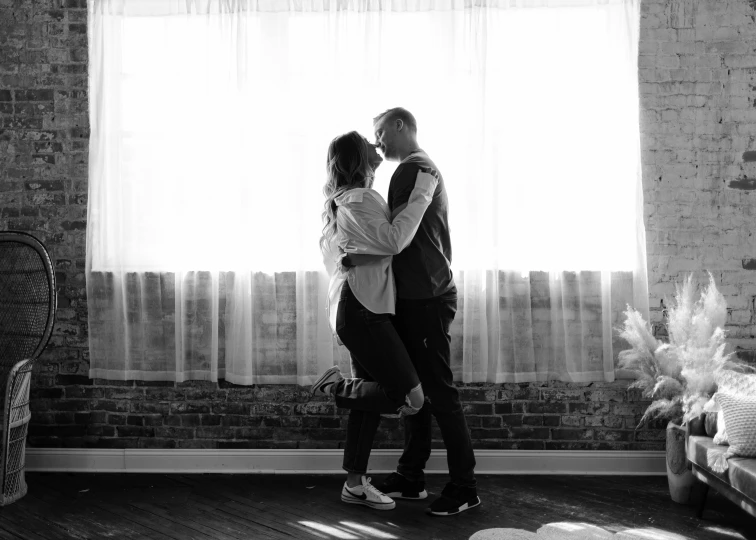 a black and white po shows an engaged couple in front of a window