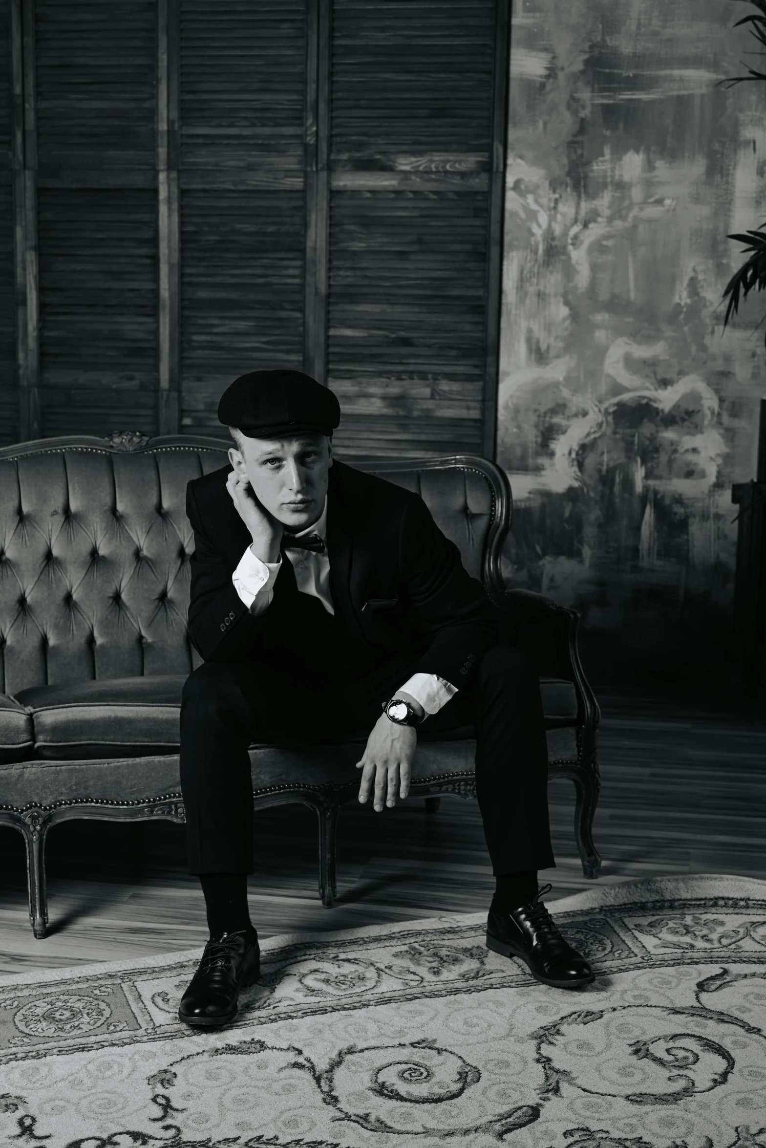 a man wearing a tuxedo and sitting on a couch