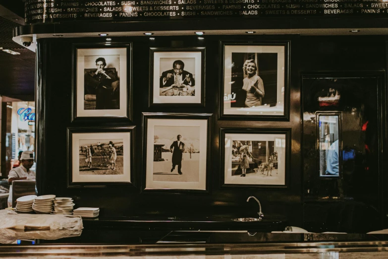 black and white pictures hang on a wall above a sink