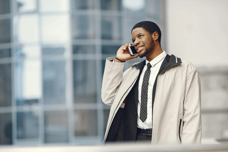 a man with tie and trench coat talks on his phone