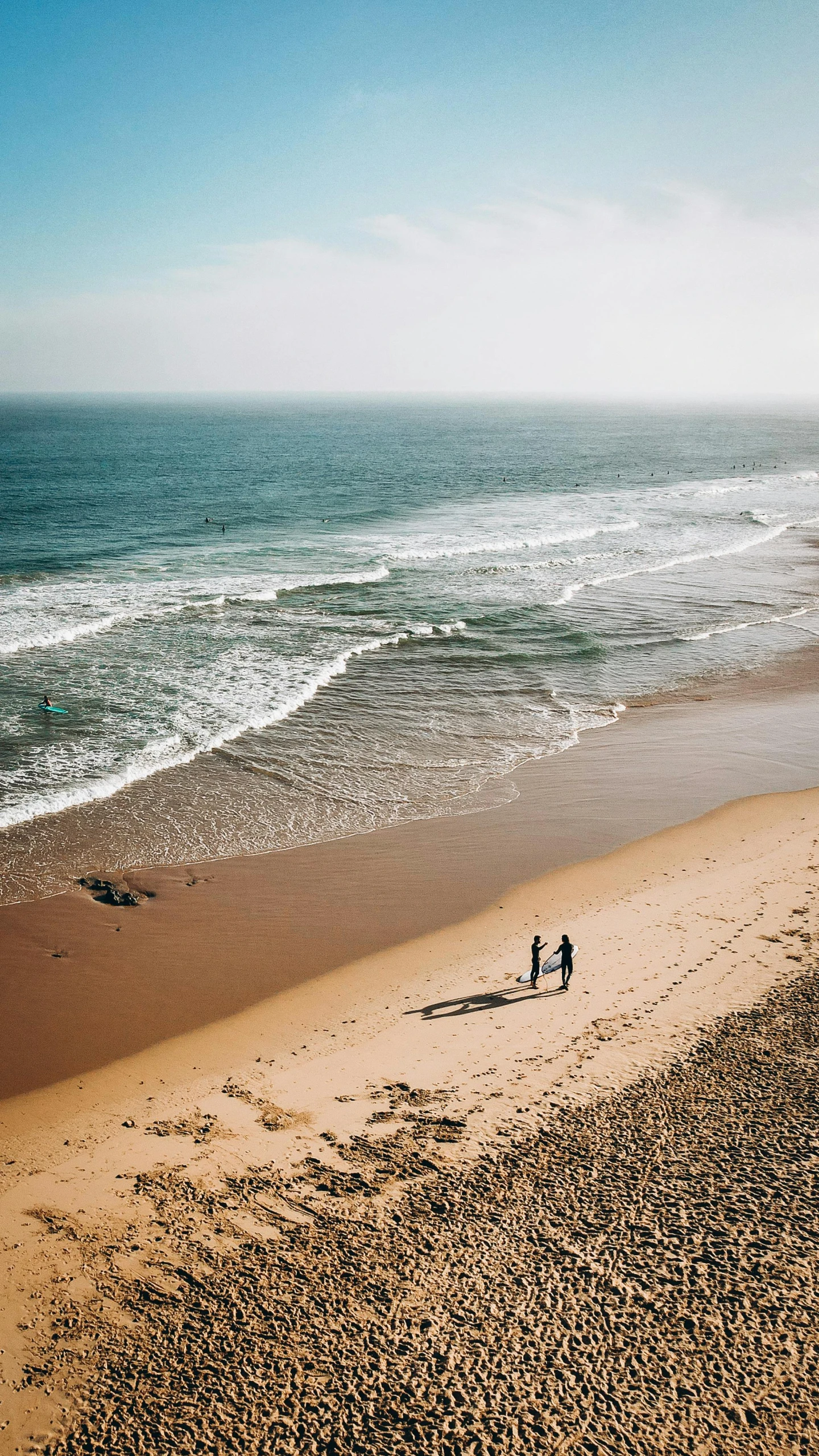 two people on the beach next to the ocean