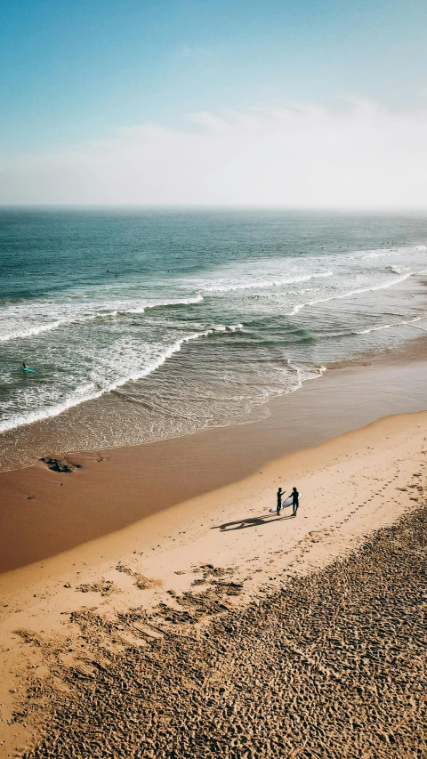 two people on the beach next to the ocean