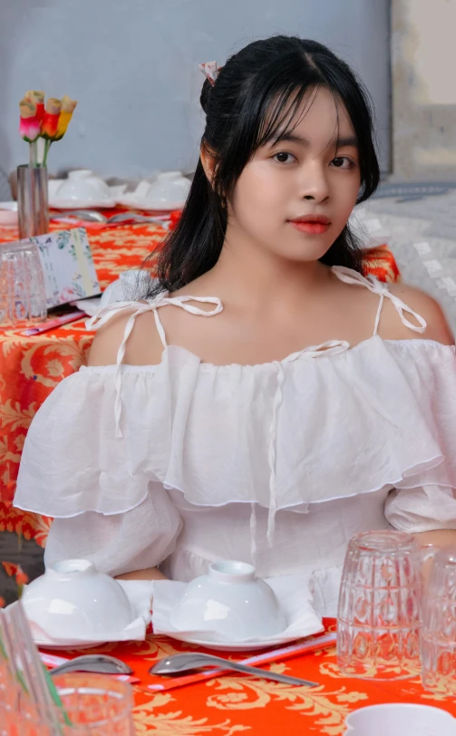 a woman with a white blouse and plates sits at a table