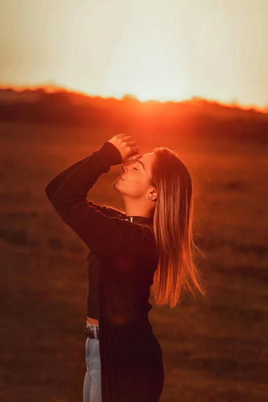 a woman stands in an open field and drinking from her glass