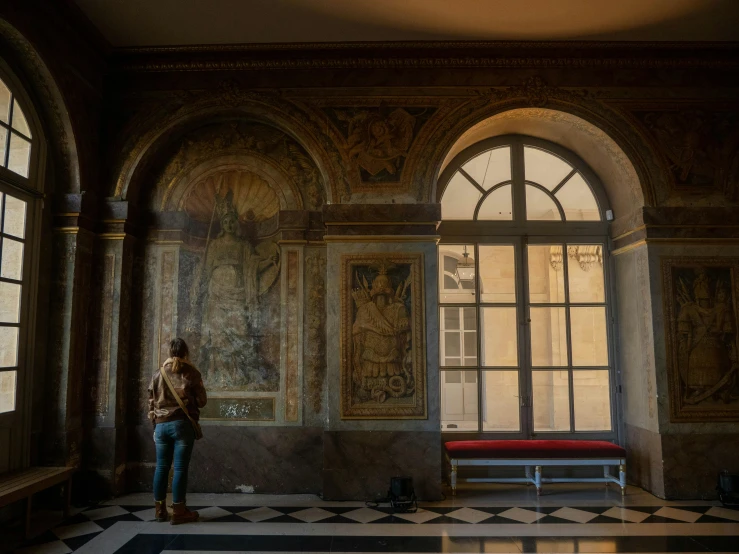 woman stands in an old looking room with a bench