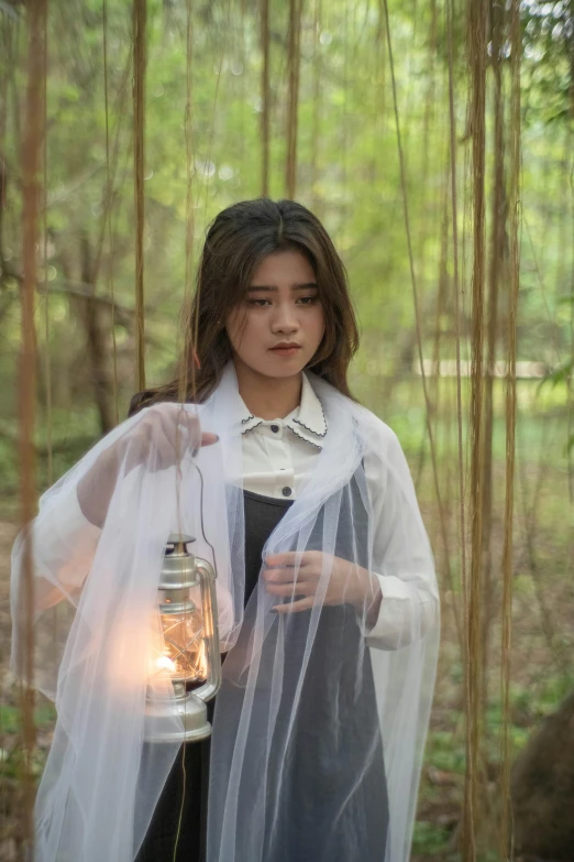 a woman in a white wedding veil holding a lantern