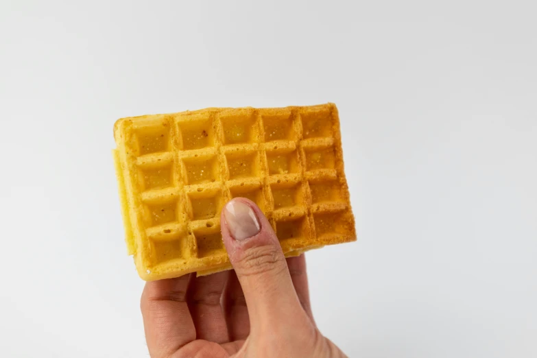 a person holding up a small waffle in their hand