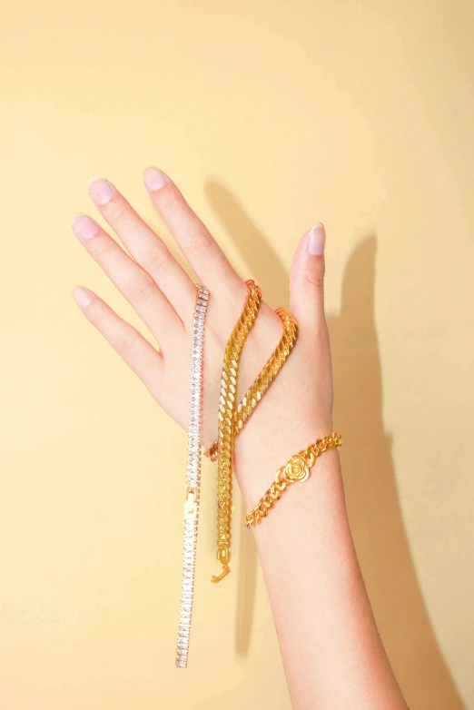 woman's hand in front of yellow background with five celets on it