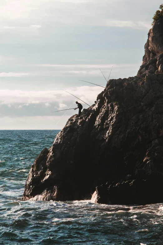 man standing on rock near body of water near large rock formation