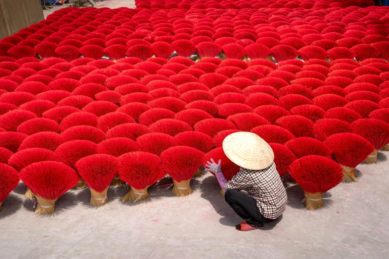 a person kneeling down in front of a large group of fake flowers