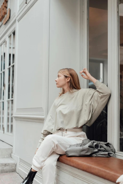 woman sitting outside of window on bench in front of building