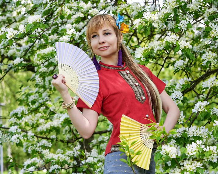 a young woman is holding a yellow and blue fan