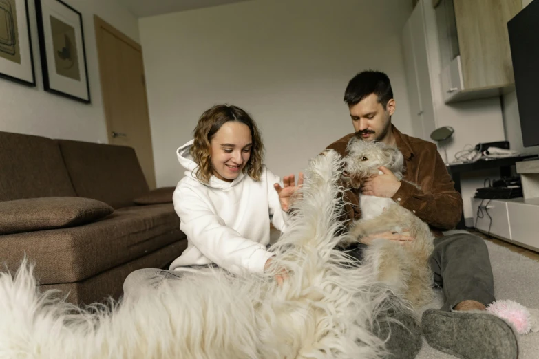 man and woman sitting on the floor playing with a gy dog