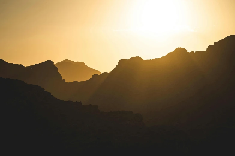 a very large mountain at sunset with the sun rising in the background