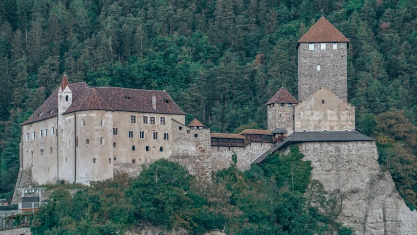 a castle perched on top of a cliff near some trees