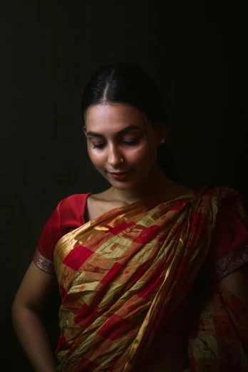 a young woman in a red and gold sari holding her hands together