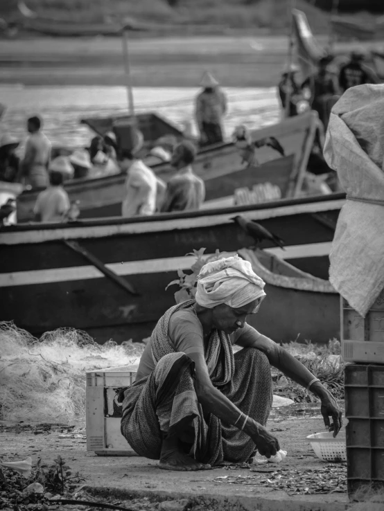 a woman sits on the ground in front of a harbor full of people