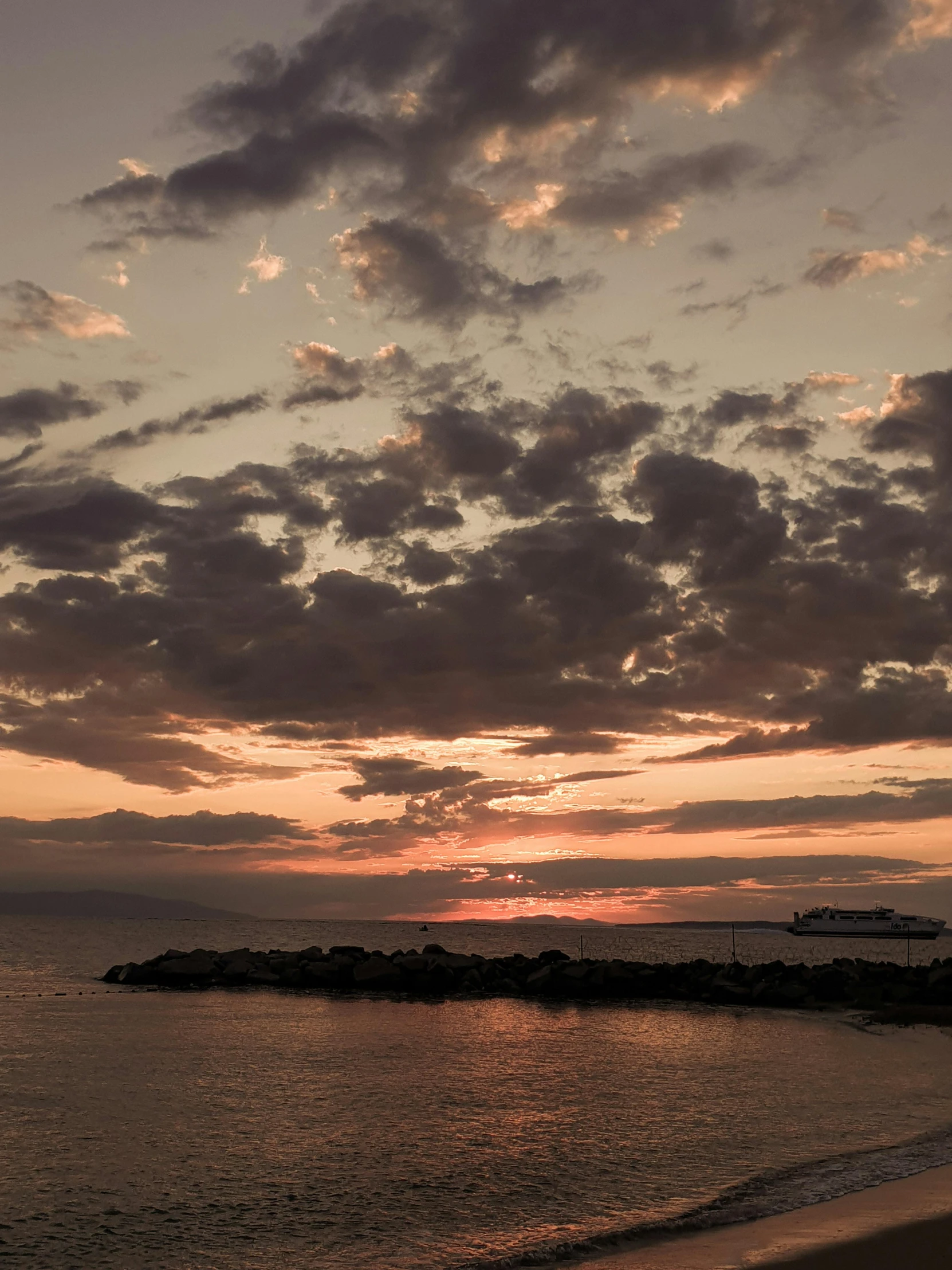 the sun setting on the water over an island