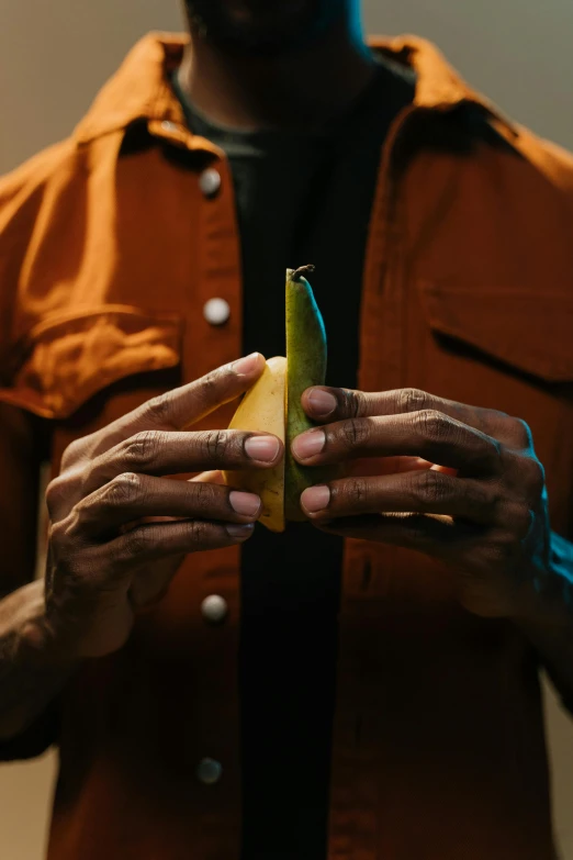 man with brown shirt holding apple and banana