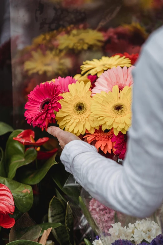 there is a person placing bright colored flowers in a pile