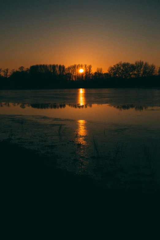 sunset and reflection of boat on water with trees