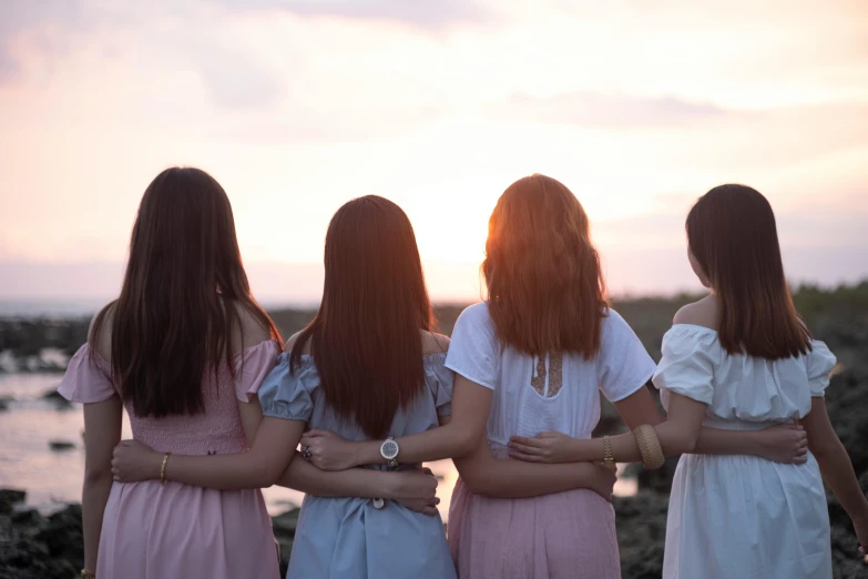 four women wearing dresses standing together in a line