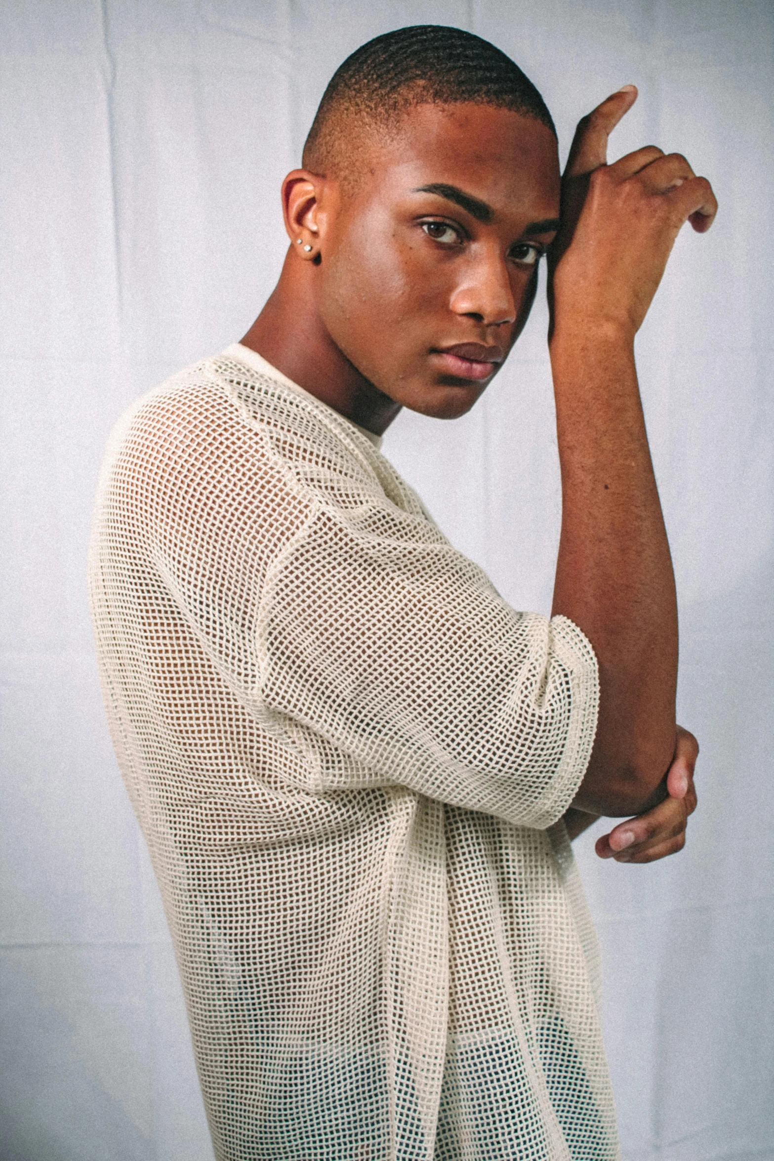 a man in a shirt standing against a white wall