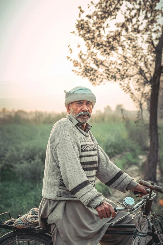 an old man sitting on a bicycle looking straight at the camera