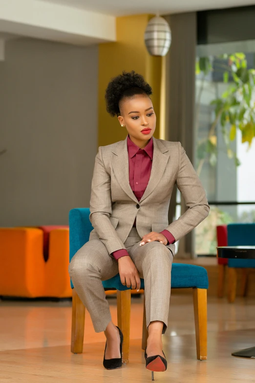 a woman sitting on a chair with red shirt and suit