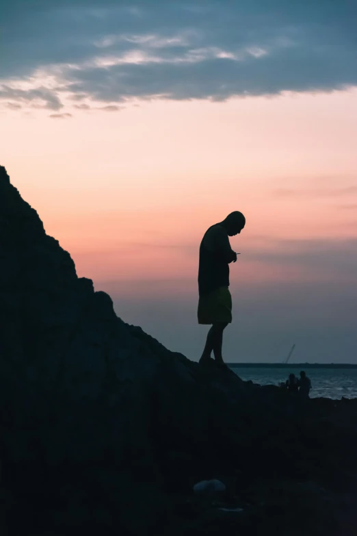 a man standing on the shore at sunset looking out into the ocean