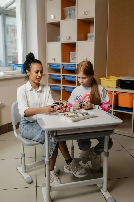 two children playing with plastic cars on their own desk