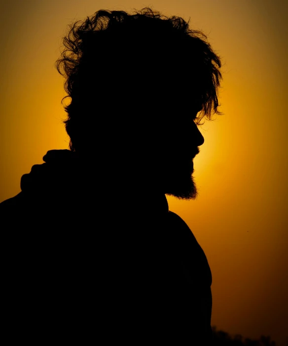 a silhouette of a man who is staring at the sunset