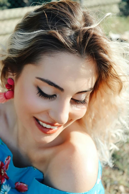 a woman is smiling while wearing bright colored earrings