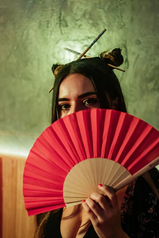 a woman wearing black holds a red fan