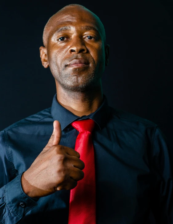 man in blue shirt and red tie giving thumbs up