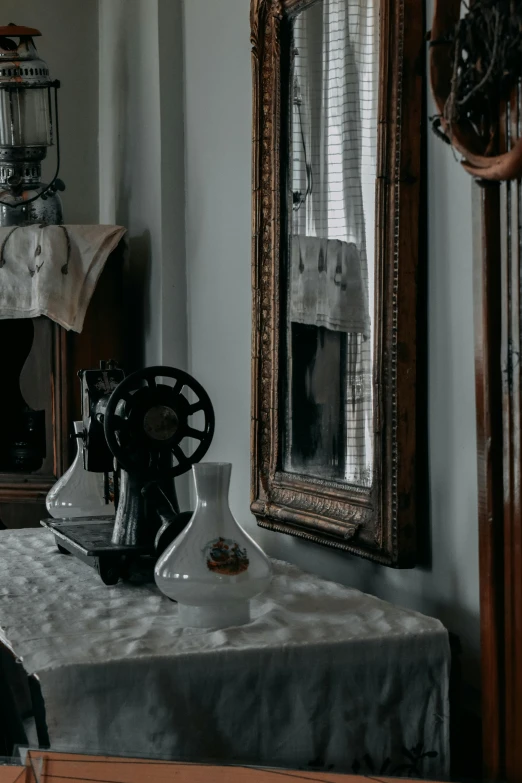 an antique sewing machine sits on a white table cloth in front of a mirror