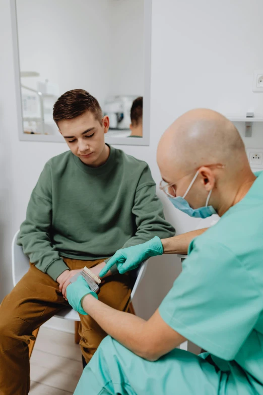 dentists wearing green gloves check up a young male patient