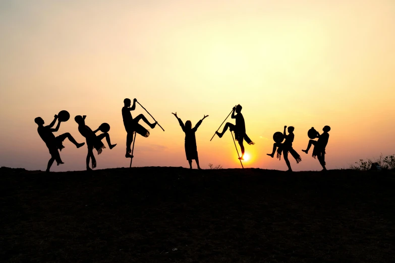 silhouettes of people standing around the letters of the word joy in front of the sun