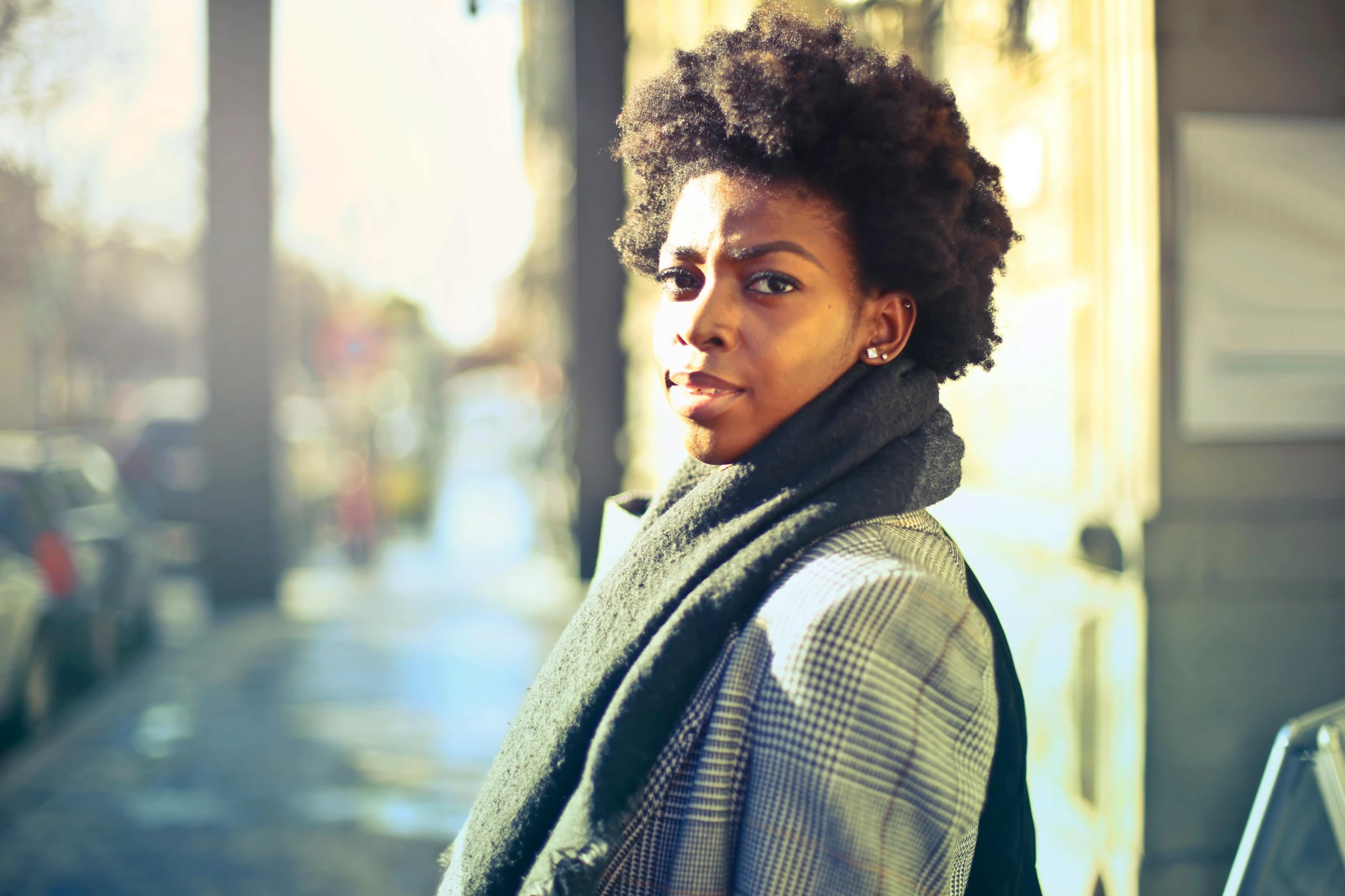 a woman in a scarf is standing on a sidewalk